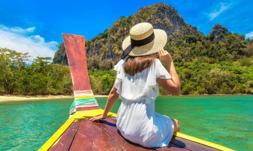 Happy traveler woman relaxing on boat near tropical island