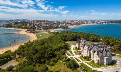 Magdalena Palace in Santander Spain with aerial view of the peninsula and the city with sunny beach in summer.